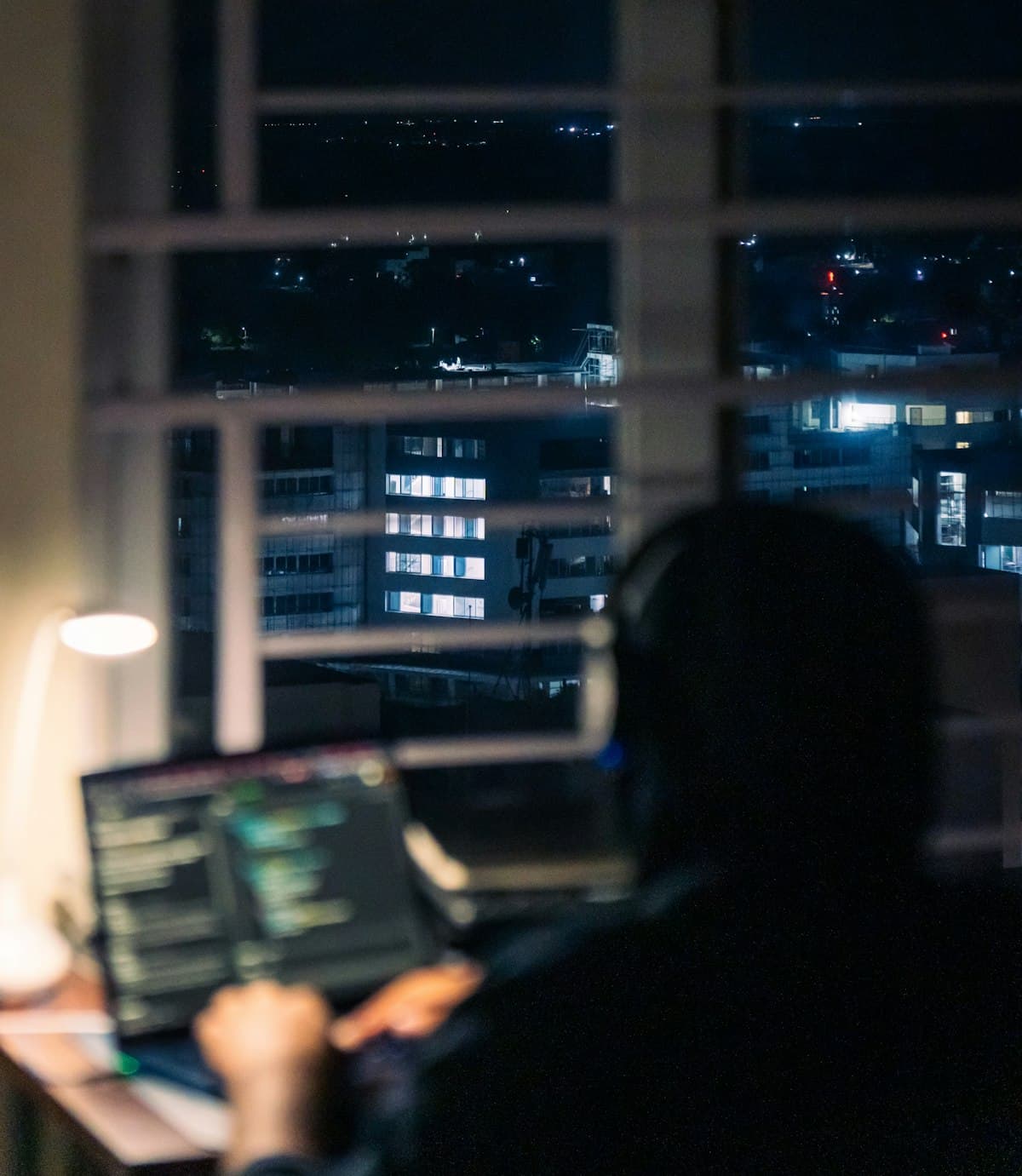 Person working at a computer at night with city lights outside
